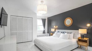 A modern bedroom with a large bed, bedside tables, a mirror, and a TV. - Stylish artistic house, close to Wynwood, Downtown (MIAMI)