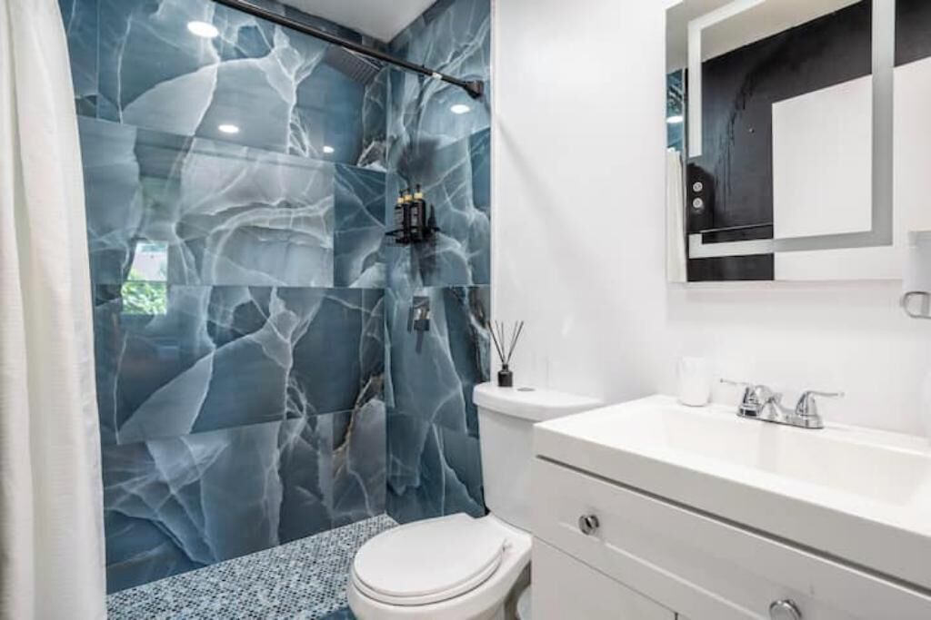 A bathroom with a white sink, a mirror, and a toilet.