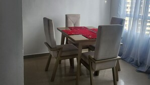 A dining area with a table and four chairs, a ceiling fan, and a window with sheer curtains. - Beautiful apartment to rest and vacation near puerto colombia. (Atlántico)