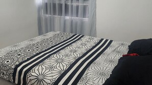 A bedroom with a bed, a window with sheer curtains, and an air conditioning unit on the wall. - Beautiful apartment to rest and vacation near puerto colombia. (Atlántico)