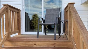 En træterrasse med stol og bord, der fører til en skydedør i glas.