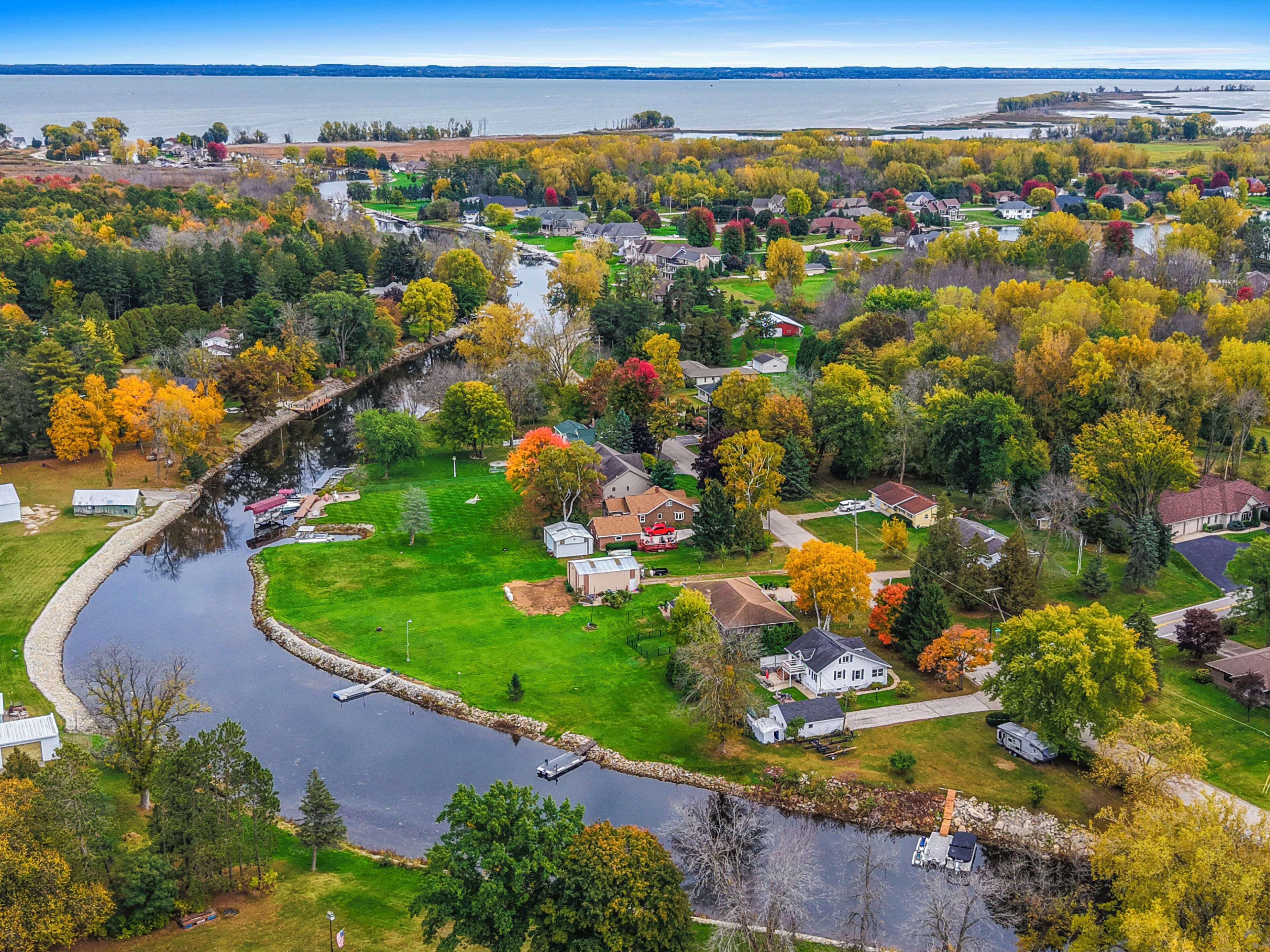 An aerial view of a residential area with houses, a river, and a bridge.