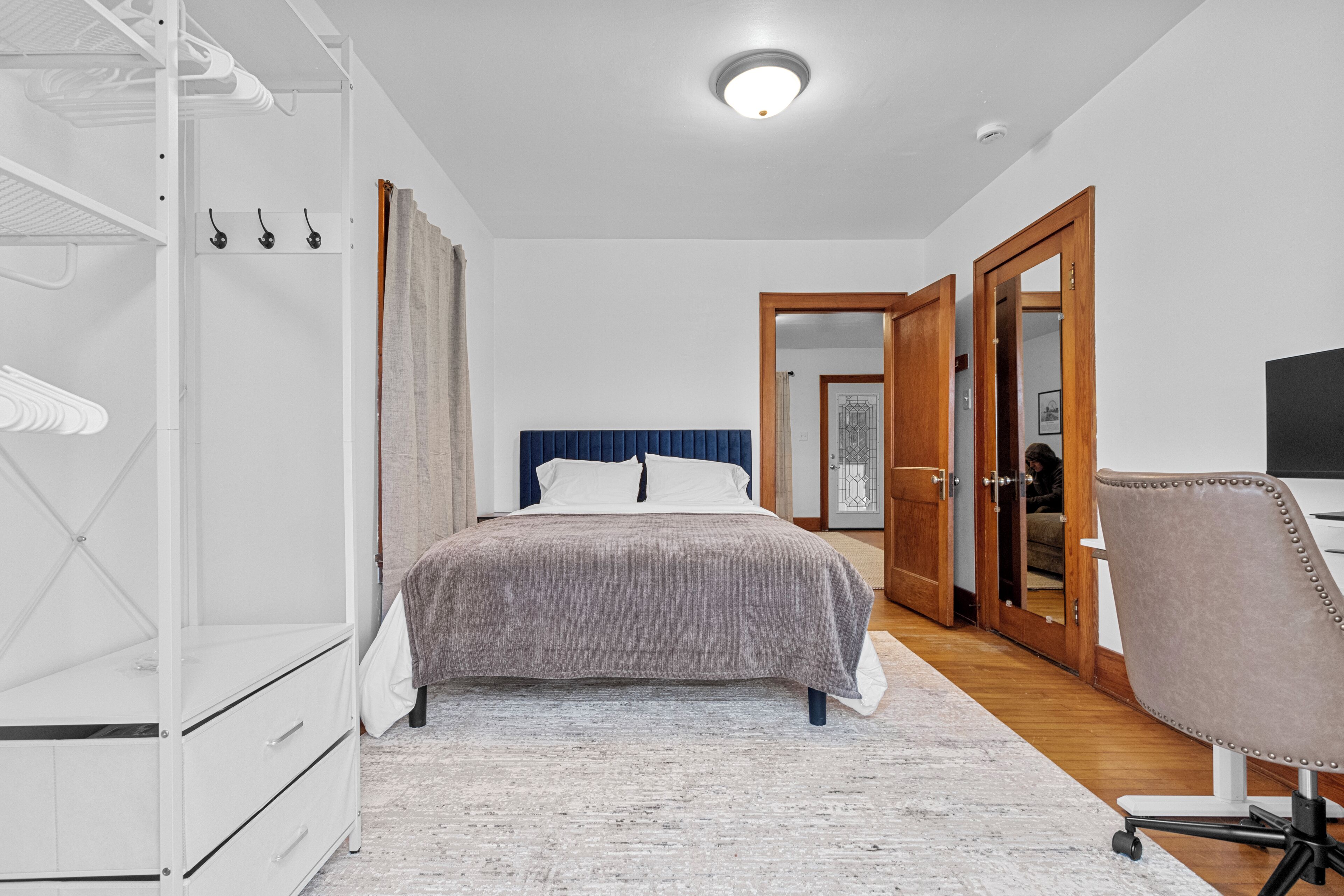 A bedroom with a bed, a wardrobe, a desk, and a chair.