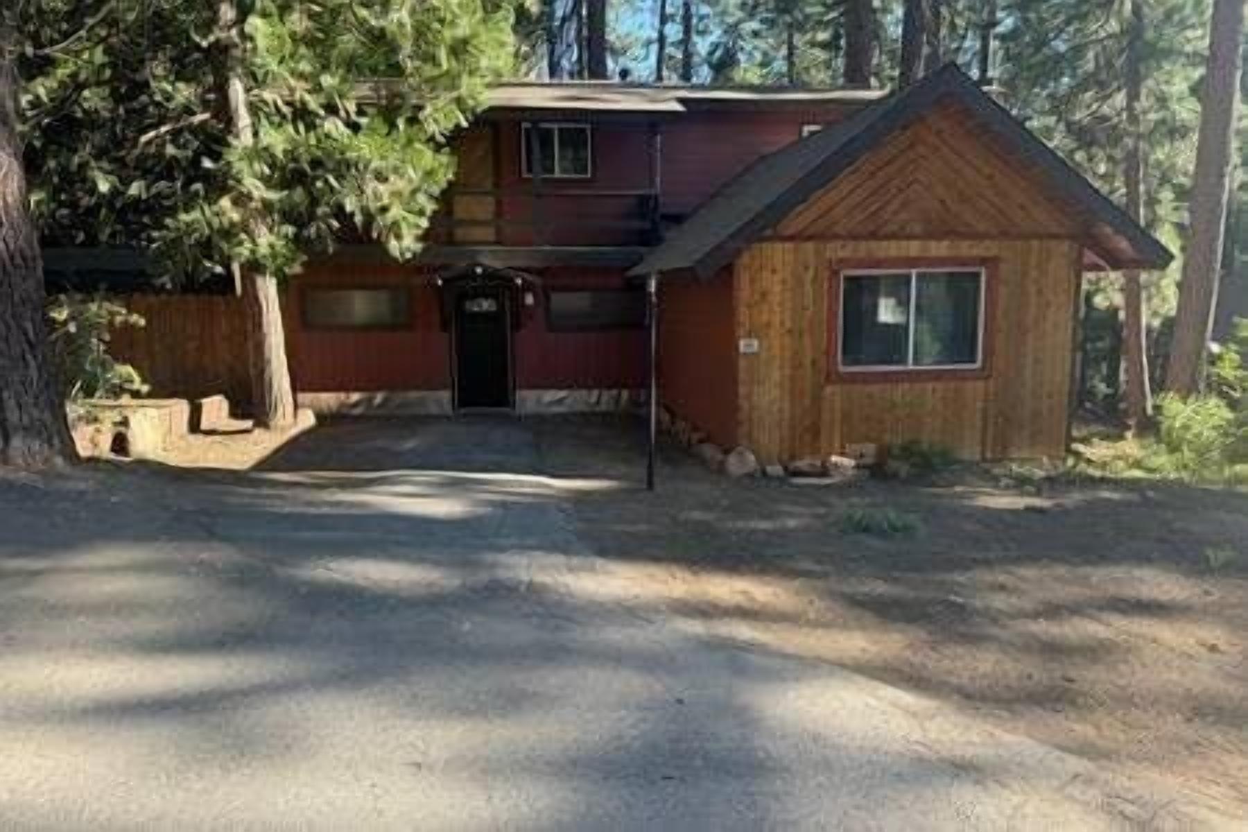 A two-story cabin with a front porch, a small attached garage, and a wooden exterior.