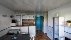 Uma cozinha compacta com armários brancos, painel de azulejos e bancada de madeira.