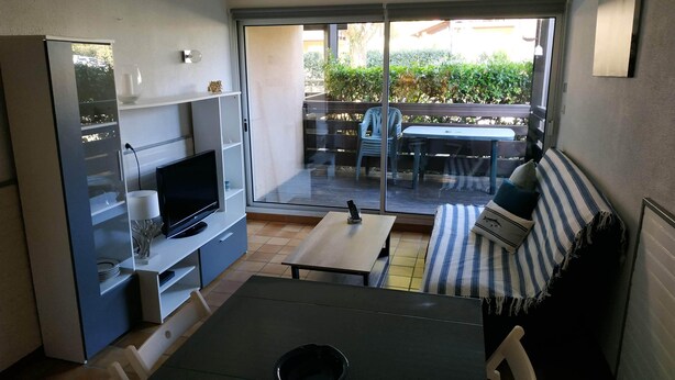 Um espaço de estar compacto com cozinha compacta, área de refeições e varanda com mobiliário de exterior.