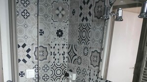 Um banheiro com pia branca, armários de madeira e azulejos estampados nas paredes.