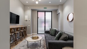 A modern living room with a grey sofa, a coffee table, and a TV mounted on the wall. - Waou Essence III Tirso Molina - Corta Duración (Madrid)
