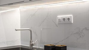 A modern kitchen with a sleek stainless steel sink, a built-in oven, and a black countertop. - Waou Essence III Tirso Molina - Corta Duración (Madrid)