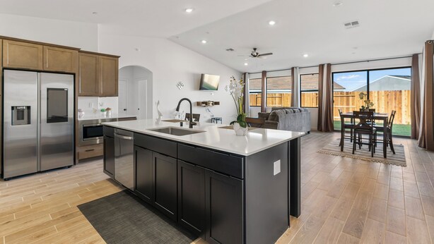 A modern kitchen with a central island, stainless steel appliances, and a dining area with a view of the backyard.