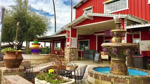 A red building with a sign reading "Murray Family Farms." There is a fountain in front, surrounded by planters and chairs.