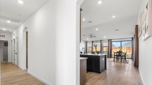 A modern kitchen with a central island, large windows, and a dining area with a view of the outdoors.