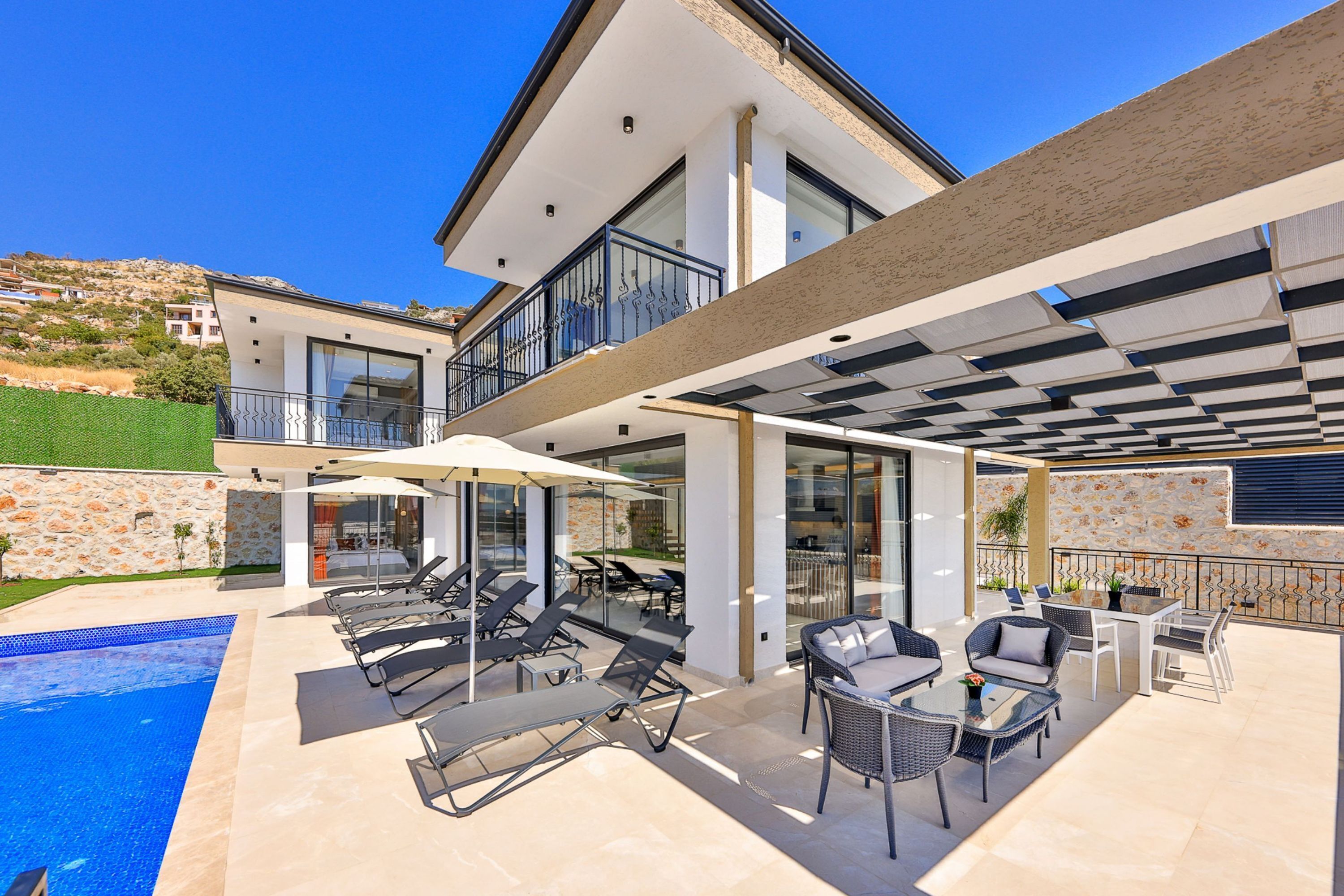 Una casa moderna con piscina, area relax esterna e un balcone.