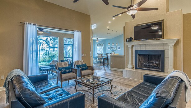 A spacious living room with leather sofas, a fireplace, and a ceiling fan. - PerfectPointeLakehouse|PvtDock|Kayaks|8ppl|Firepit|ScreenedPatio (Hernando)