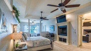 A spacious bedroom with a large bed, a ceiling fan, a fireplace, and a view of the outdoors. - PerfectPointeLakehouse|PvtDock|Kayaks|8ppl|Firepit|ScreenedPatio (Hernando)