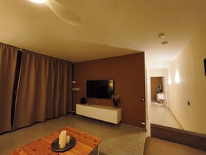 A modern living room with a flat-screen TV, a wooden coffee table, and a sofa.