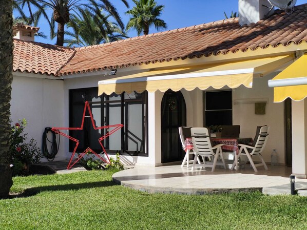A patio with a table and chairs, a star decoration, and a yellow awning.