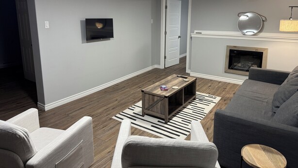 A modern living room with a grey sofa, a wooden coffee table, and a fireplace. - Relaxing Lake Haven | Peaceful (Saint John)