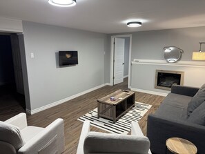 Un salon moderne avec un canapé gris, une table basse en bois et une cheminée.