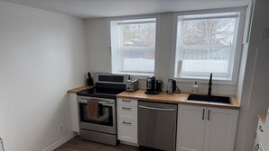 A compact kitchen with a stove, oven, dishwasher, and a sink. - Relaxing Lake Haven | Peaceful (Saint John)