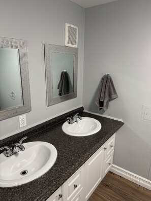 Une salle de bain avec deux lavabos, un miroir et un porte-serviettes.