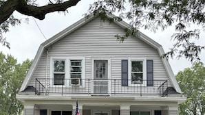 A two-story house with a front porch, a flag, and a wreath.
