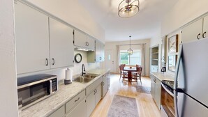 A modern kitchen with a built-in microwave, stainless steel sink, and a dining area with a table and chairs.