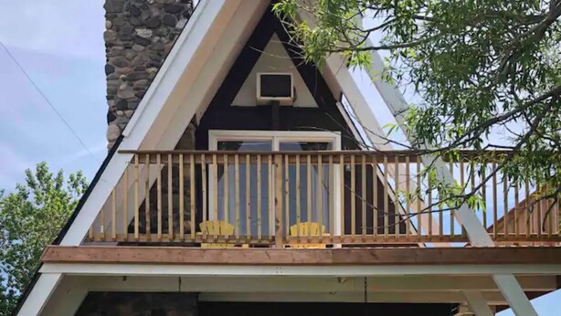 Une maison à deux étages dotée d’un balcon, d’une façade en pierre et d’une terrasse avec des sièges d’extérieur.