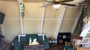 Un salon chaleureux avec un canapé vert, une commode en bois et un fauteuil à bascule en bois.
