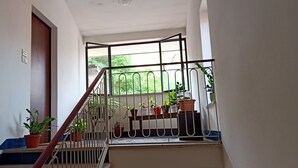 Una escalera con barandilla de metal, plantas en macetas y vistas al verdor exterior.