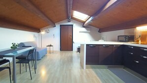Cocina compacta con vigas de madera, comedor con mesa y sillas, y una pequeña kitchenette.