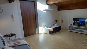 Una sala de estar moderna con techo de madera, un sofá, una mesa de centro, un televisor y una mesita auxiliar.
