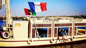A boat with a flag, a person, and a view of the water.