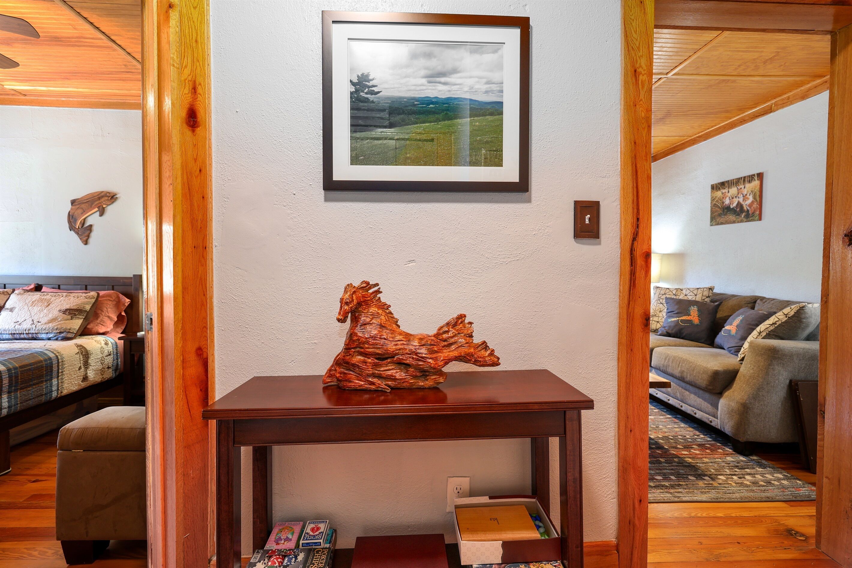A living room with a wooden table, a framed landscape painting, and a sofa.