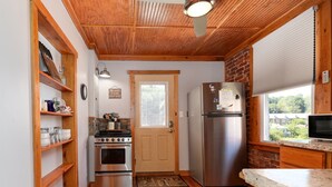 A compact kitchen with wooden flooring, a stainless steel refrigerator, an oven, and a sink.
