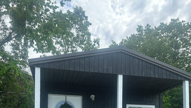 A small, single-story building with a white door, a window, and a porch with a railing. - Bear Cub ,Cozy cabin with WiFi and AC in peaceful Stevenson (Stevenson)