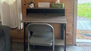 A cozy room with a wooden wall, a small table with a chair, a sign, and a window with a view of a house. - Bear Cub ,Cozy cabin with WiFi and AC in peaceful Stevenson (Stevenson)