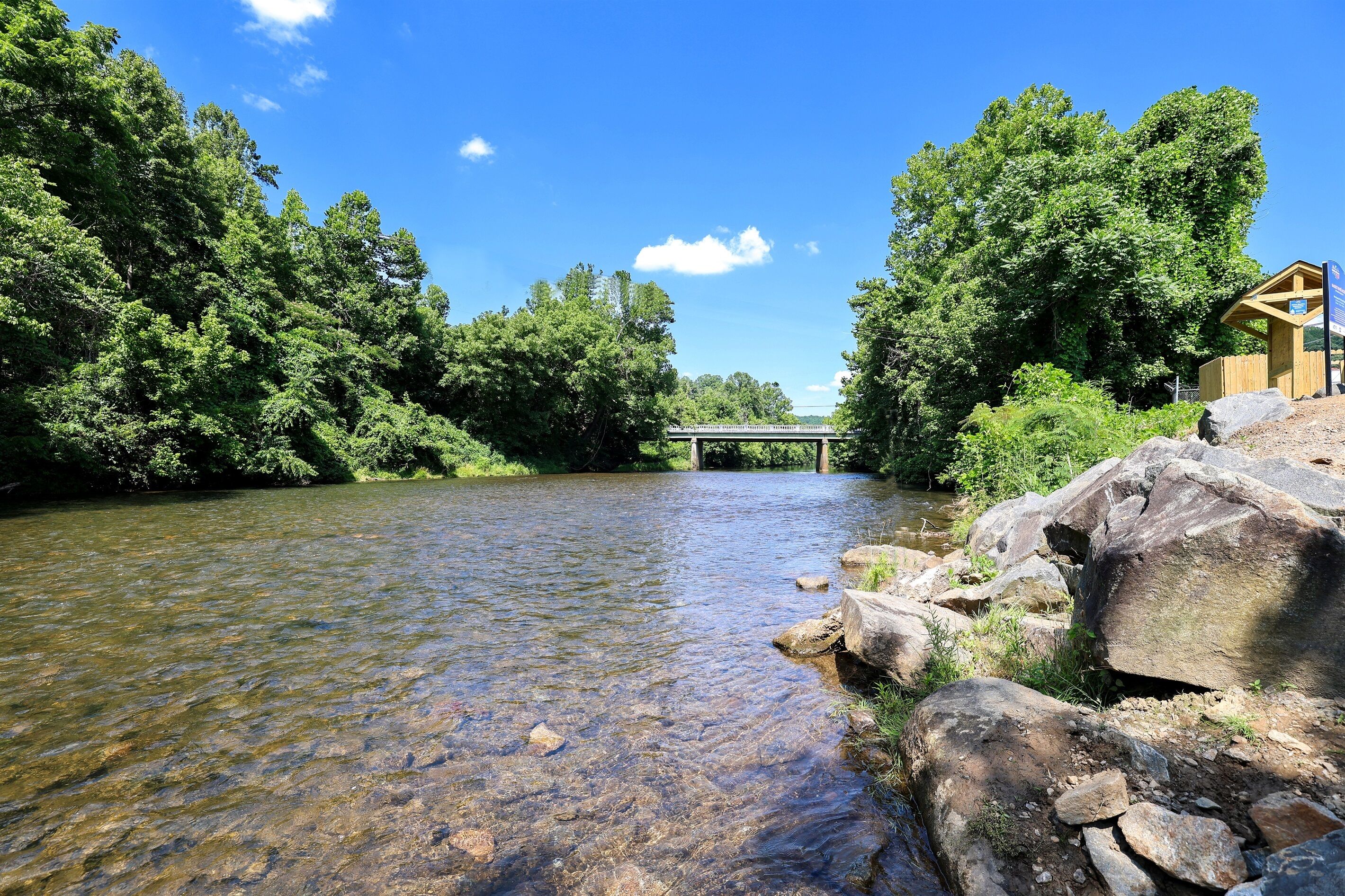 A river with a wooden structure on the right and a bridge in the background.