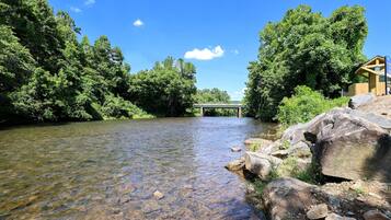 A river with a wooden structure on the right and a bridge in the background.