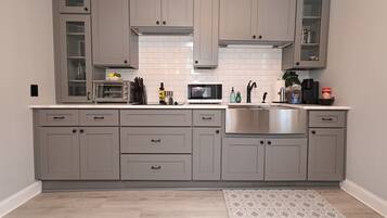 Une cuisine moderne avec des meubles gris, un évier en acier inoxydable et un four à micro-ondes.