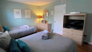 Camera d'albergo con due letti, televisione, comò e specchio.