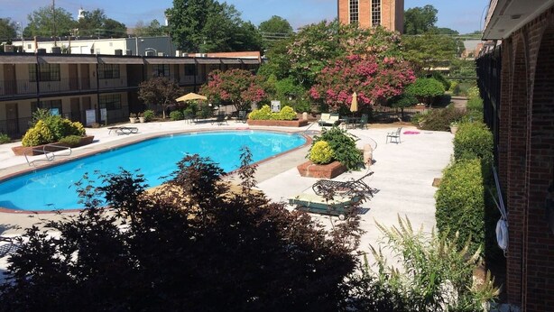 Una piscina con lettini e un edificio in mattoni sullo sfondo.