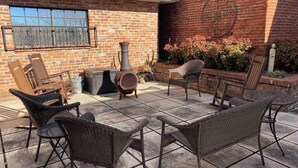 Una terrazza esterna con mobili in vimini, un muro in mattoni e un elemento decorativo in metallo.