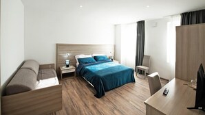 A modern hotel room with a bed, a desk, a chair, and a wardrobe. - B&B Luna Suite & Room (Rubiera)