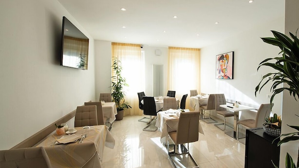 A modern dining area with tables and chairs, a large potted plant, and artwork on the walls. - B&B Luna Suite & Room (Rubiera)