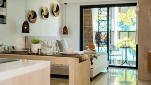Una cocina moderna con encimera de madera, un comedor con mesa preparada para dos personas y vistas al exterior a través de un gran ventanal.