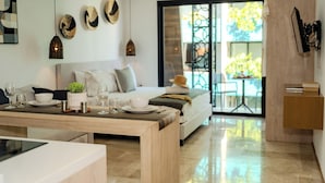 Una sala moderna con sofá, mesa de comedor y vistas al exterior a través de un ventanal.
