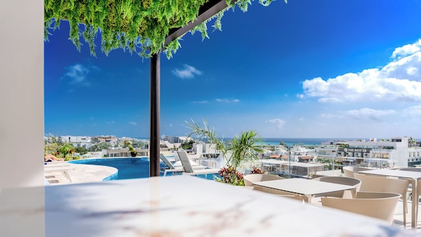 Un área de piscina en la azotea con vistas despejadas al paisaje urbano y al mar.