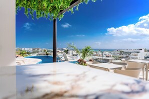 Un área de piscina en la azotea con vistas despejadas al paisaje urbano y al mar.