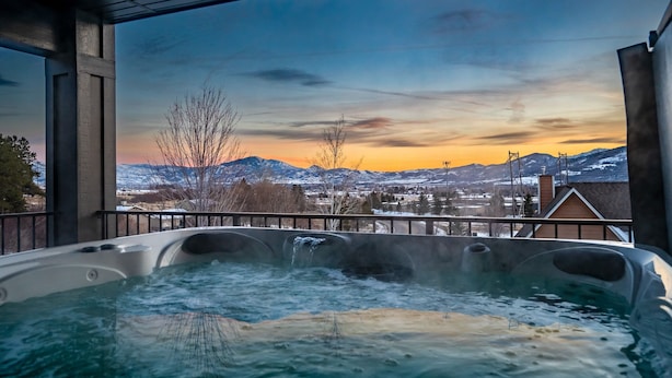 Un jacuzzi con vistas a montañas y al atardecer.